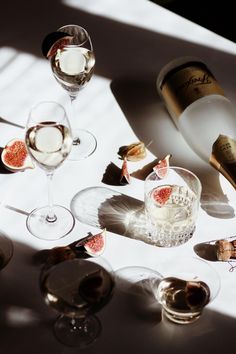 several wine glasses on a table with some food in the middle and one empty bottle next to it