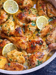 a pan filled with chicken and lemons on top of a table