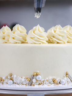 a cake with white frosting and gold decorations is being cut into by a knife