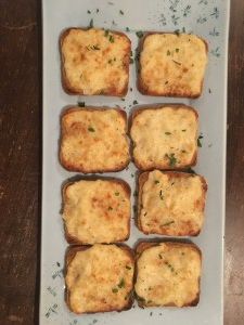 several pieces of bread with cheese on them sitting on a white plate next to a wooden table