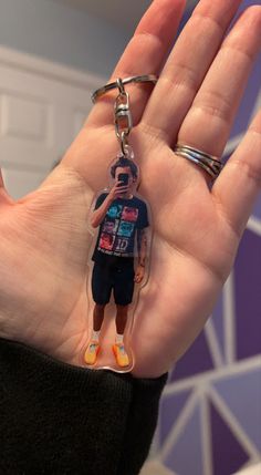 a hand holding a keychain with a person wearing a shirt and shorts on it