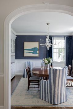 a dining room with blue walls and striped chairs