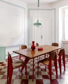 a dining room table with chairs and a vase on top of it in front of a checkered floor