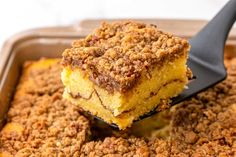 a close up of a spoonful of food in a casserole dish with crumbs