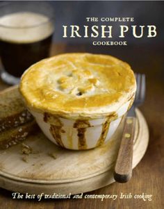 the complete irish pub cookbook is on a wooden plate with two forks and spoons