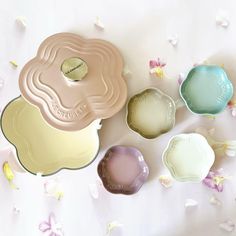 four different colored dishes sitting next to each other on a white surface with pink and yellow flowers