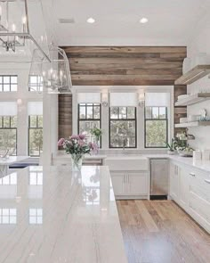 a large kitchen with white cabinets and marble counter tops, along with wood paneling on the walls