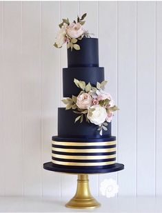 a three tiered blue and gold wedding cake with flowers on the top is shown