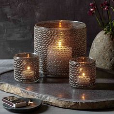 three candles sitting on top of a table next to a vase with flowers in it