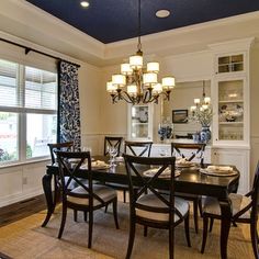 a dinning room table with chairs and a chandelier in front of the window