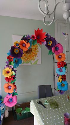 an arch made out of paper flowers on a dining room table