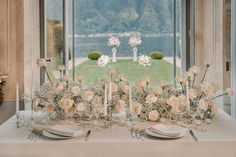 the table is set with white flowers and place settings