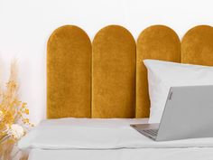 an open laptop computer sitting on top of a bed next to pillows and vases