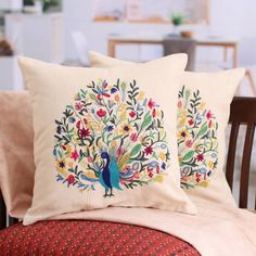 two decorative pillows on a chair in a room with a table and chairs behind them