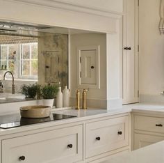 a kitchen with white cabinets and marble counter tops, gold faucet handles on the sink