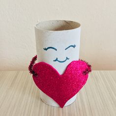 a paper cup with a heart shaped face on the inside, sitting on a table