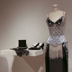 a woman's dress and hat on display in a room with mannequins