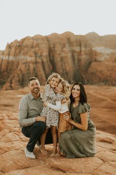 three adults and two children sitting on rocks in the desert