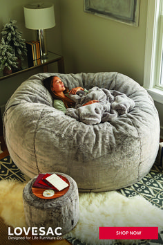 a woman laying in a bean bag chair on top of a fur rug next to a lamp