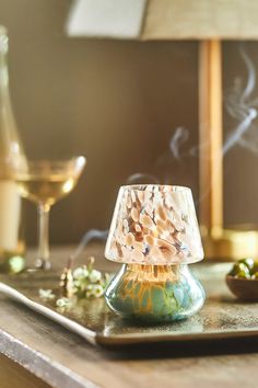 a lamp sitting on top of a wooden table next to a wine glass and other items