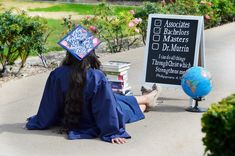 a woman sitting on the ground in front of a sign with books and a globe