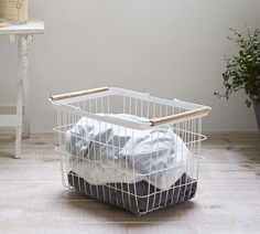 a laundry basket with clothes in it sitting on the floor next to a white table