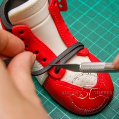 someone is cutting the bottom part of a red shoe with a pair of pliers