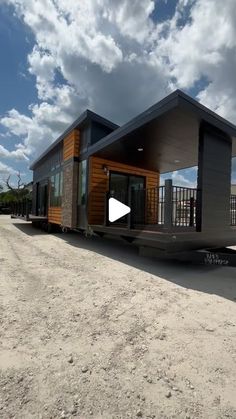 a tiny house sitting on the back of a trailer in front of a cloudy sky