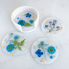 four plates with blue flowers on them sitting on a white counter top next to each other