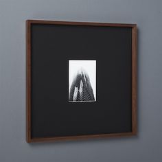 a black and white photo hanging on the wall next to a wooden frame with a building in it