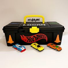 toy cars are lined up in front of a black toolbox with the word hot wheels written on it