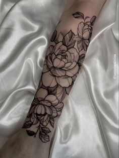 a black and white flower tattoo on the arm