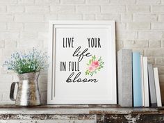 there is a vase with flowers and books on the shelf next to it that says live your life in full bloom