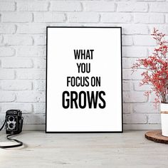 a black and white poster with the words what you focus on grows next to a camera