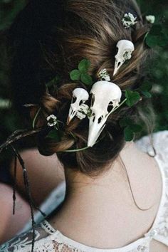 a woman with flowers in her hair and two white skulls on the back of her head