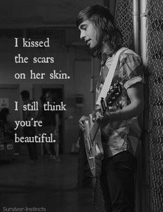 a man standing next to a chain link fence with a guitar in his hand and the words i kissed the scars on her skin, i still think you're beautiful