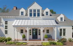 a white house with two large windows and a covered front porch is seen in this image