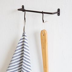 two tea towels hanging on a hook with a wooden spoon next to one that is holding a towel