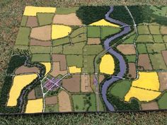 a patch of grass with yellow and green fields painted on it in the shape of a map