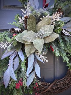 a wreath is hanging on the front door with evergreens and other greenery around it