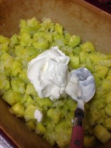 a wooden bowl filled with food next to a knife and some sour cream on top