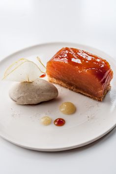 a white plate topped with a piece of cake next to a potato on top of it