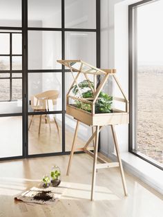 an indoor planter with plants in it sitting on a wooden stand next to a window