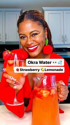 a woman holding up a sign that says okra water and strawberry lemonade in front of her