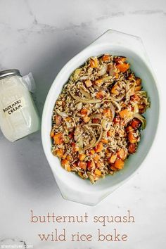 a white bowl filled with food next to a jar of butternut squash wild rice bake