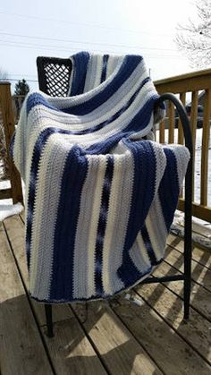 a blue and white striped blanket sitting on top of a wooden deck next to a chair