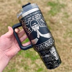 a hand holding a black and silver coffee cup with an image of elvis presley on it