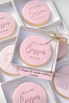 four decorated cookies in pink and white boxes with the names of their wedding day written on them