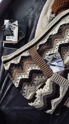 a crocheted sweater sitting on top of a couch next to an open book