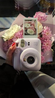 a person holding a camera with flowers in the background